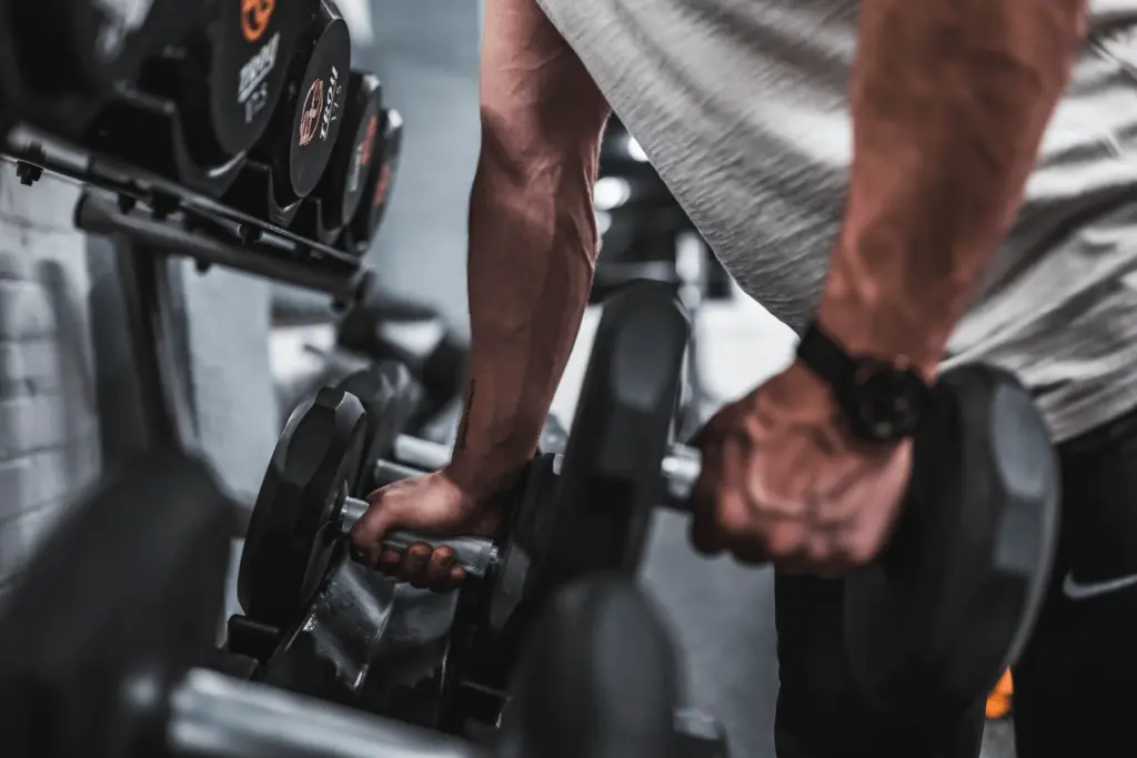 Athlète soulevant des haltères dans une salle de sport pour renforcer les bras et le haut du corps.