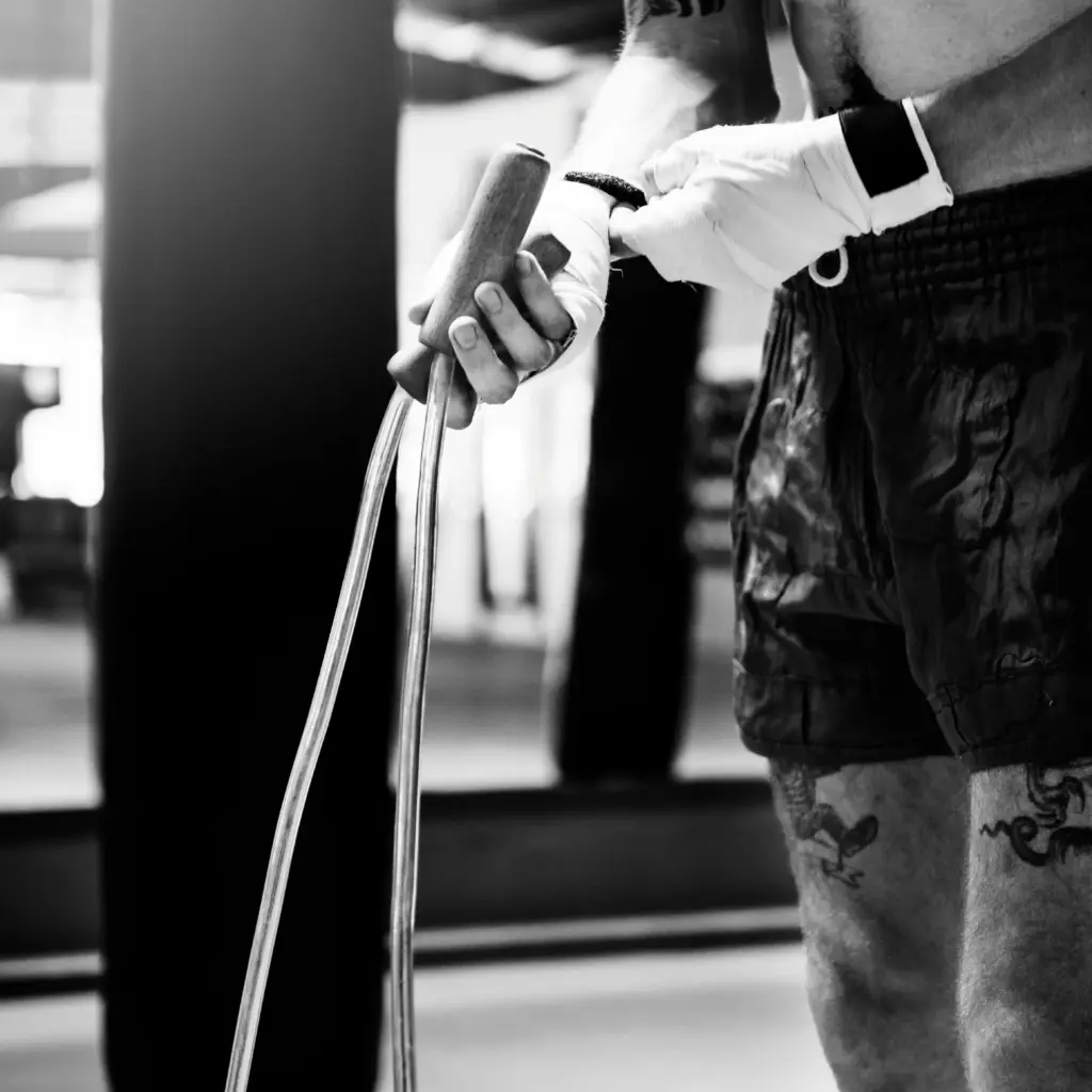 Sportif ajustant ses bandes de poignets tout en tenant une corde à sauter avant une séance d'entraînement.