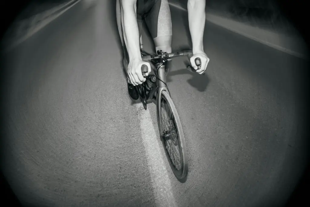Cycliste en position aérodynamique roulant sur une route lors d'un entraînement de performance.